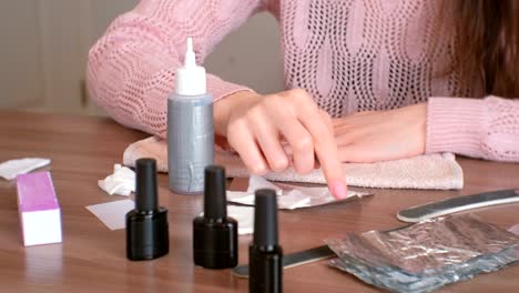 Removing-gel-Polish-from-nails.-Woman-pours-remove-liquid-on-a-cotton-pad,-puts-it-on-a-nail-and-wraps-the-foil.-Close-up-hands.