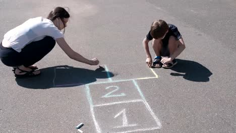 Mother-and-son-drawing-together-hopscotch-on-the-pavement.