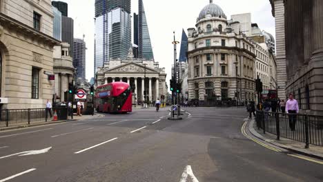 Red-double-decker-bus-passing-during-morning-rush-hour-in-the-financial-district-London,-UK.