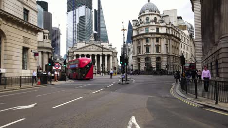 Autobús-rojo-de-dos-pisos-pasando-durante-hora-de-acometidas-de-la-mañana-en-el-distrito-financiero-de-Londres,-Reino-Unido.