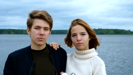 Portrait-of-two-teenagers,-a-guy-and-a-girl,-against-the-background-of-a-river-and-forest.