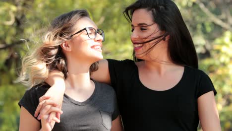 Two-girlfriends-together-walking-at-the-park-embracing-and-kissing-each-other.-LGBT-couple-kiss.