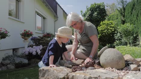 Großmutter-und-Kind-spielt-in-der-Nähe-von-Garten-Wasser-Brunnen