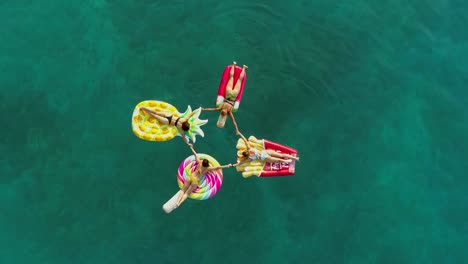 Aerial-view-group-of-women-holding-hands-on-inflatable-mattress-on-Atokos.