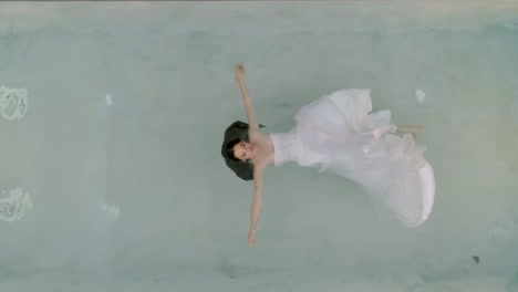 Aerial-view-of-a-woman-floating-in-the-water-using-a-wedding-dress,-Greece.