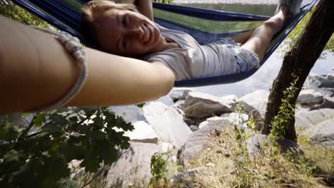 Joven-teniendo-selfie-en-hamaca-relajante-por-el-río-en-verano.-Tiempo-SELFIE