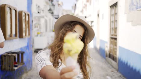 Smiling-woman-eating-ice-cream-on-town-street