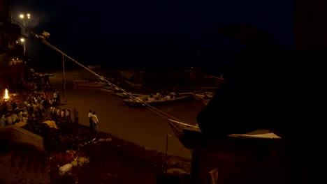 Night-smashan-with-funeral-pyres-people-throng-on-stairs-flood-of-Ganga-boats-on-pire-pile-of-wood-silhouette-of-cow-in-front-Manikarnika-ghat