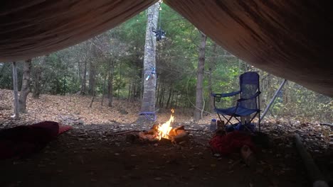 Wasserkocher-und-Topfaufhänger-mit-Lagerfeuer-und-Lichterketten.-Survival-Bushcraft-Setup-in-den-Blue-Ridge-Mountains-in-der-Nähe-von-Asheville.-Primitive-Tarp-Shelter