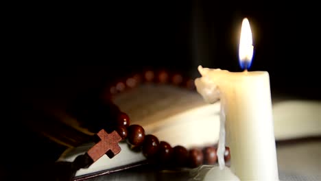 Candle-burning-on-the-background-of-the-holy-book-and-a-cross