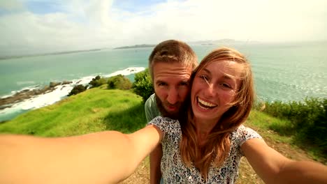 Young-couple-take-a-selfie-portrait-over-grassy-coastline-hill