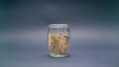 Mujer-pone-Canadá-dólar-100-en-un-tarro-de-cristal