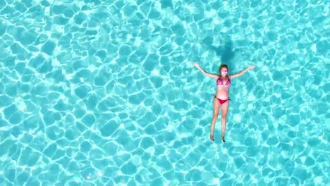 Aerial-view-of-an-attractive-woman-floating-in-turquoise-sea