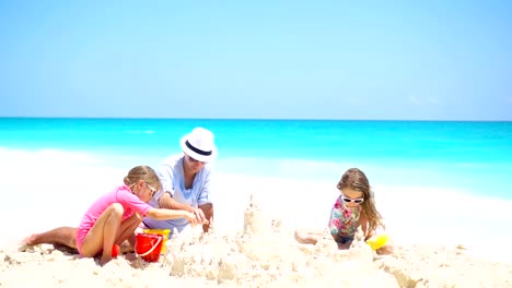 Padre-y-los-niños-haciendo-castillos-de-arena-en-la-playa-tropical