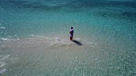 v03928-Aerial-flying-drone-view-of-Maldives-white-sandy-beach-2-people-young-couple-man-woman-romantic-love-on-sunny-tropical-paradise-island-with-aqua-blue-sky-sea-water-ocean-4k