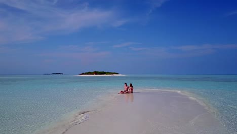 v03995-Aerial-flying-drone-view-of-Maldives-white-sandy-beach-2-people-young-couple-man-woman-romantic-love-on-sunny-tropical-paradise-island-with-aqua-blue-sky-sea-water-ocean-4k