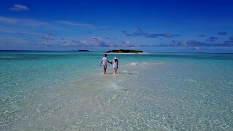 v03914-Aerial-flying-drone-view-of-Maldives-white-sandy-beach-2-people-young-couple-man-woman-romantic-love-on-sunny-tropical-paradise-island-with-aqua-blue-sky-sea-water-ocean-4k
