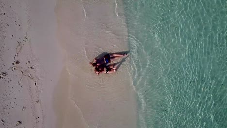 v03897-Aerial-flying-drone-view-of-Maldives-white-sandy-beach-2-people-young-couple-man-woman-romantic-love-on-sunny-tropical-paradise-island-with-aqua-blue-sky-sea-water-ocean-4k