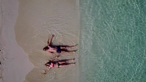 v03865-Aerial-flying-drone-view-of-Maldives-white-sandy-beach-2-people-young-couple-man-woman-romantic-love-on-sunny-tropical-paradise-island-with-aqua-blue-sky-sea-water-ocean-4k