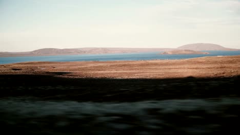 View-inside-the-car-of-beautiful-sunset-landscape-of-mountains-and-water,-lake.-View-of-the-vehicle-shadow-outside