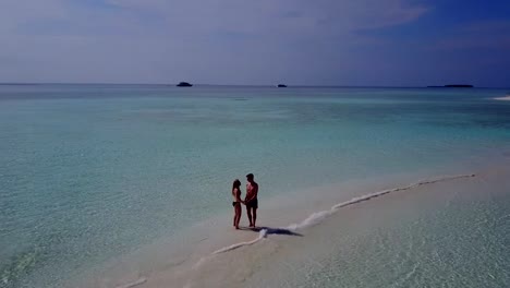 v03959-vuelo-drone-vista-aérea-de-Maldivas-playa-2-personas-pareja-hombre-mujer-amor-romántico-en-la-isla-de-paraíso-tropical-soleado-con-cielo-azul-aqua-agua-mar-4k