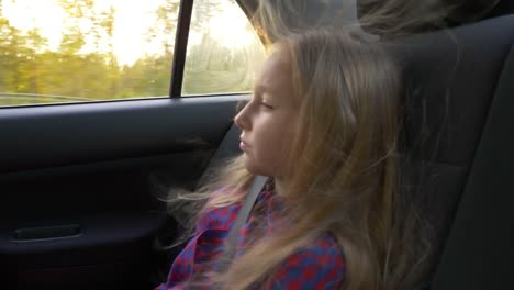 Young-beautiful-girl-on-adventure-road-trip-inside-car-the-wind-in-her-hair.-Pretty-serious-white-girl.-Road-speed-drive-strong-wind.-Travel-autumn-sunset.-Backlit-light-sunbeam.