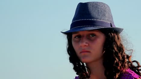 Retrato-de-bella-joven-con-sombrero-de-paja-en-la-playa,-sonriendo-a-cámara