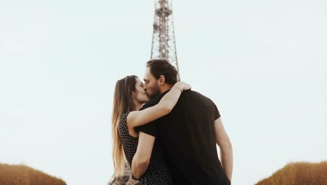 Joven-pareja-feliz-caminar-cerca-de-la-Torre-Eiffel-en-París,-Francia.-Mirada-de-hombre-y-mujer-y-monumento-y-levanta-las-manos