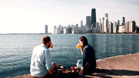 Cita-romántica-en-la-costa-del-lago-Michigan-en-Chicago,-América.-Hermosa-pareja-disfrutando-de-un-picnic-juntos
