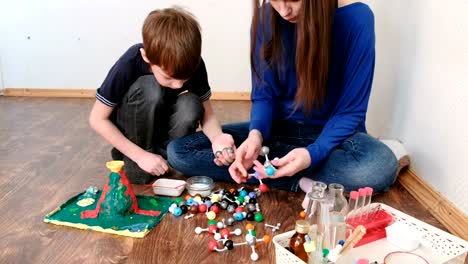 Mom-with-son-building-molecule-models-of-colored-plastic-construction-set.