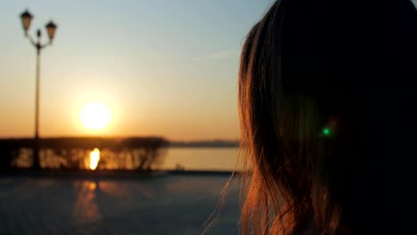 profile-view-of-girl-sipping-drink-from-cardboard-cup-in-evening-on-a-city-quay