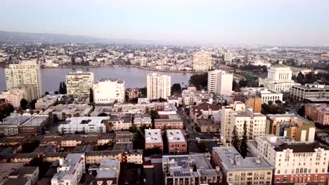 Al-atardecer-cae-sobre-los-edificios-y-la-ciudad-de-Oakland,-California-y-lago-Merritt