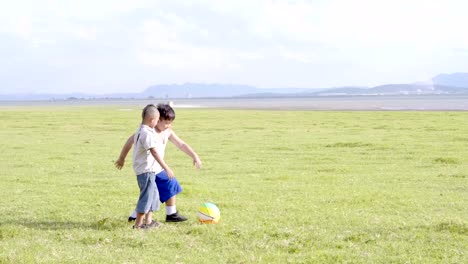 Zwei-asiatische-Jungs-Fußball-spielen,-Spaß,-glücklich.-Die-ländlichen-Prärie-Hintergrund.-4K-Video-Zeitlupe