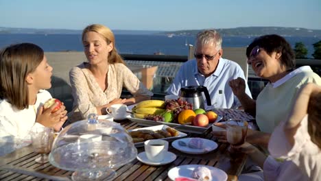 Eine-große,-glückliche-Familie-hat-Abendessen-auf-der-Terrasse-auf-dem-Dach-des-Hauses.