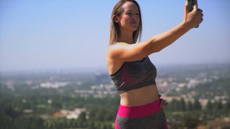Slow-Motion-junge-Frau-in-ihre-Trainingskleidung-unter-malerischen-Selfies-mit-ihrem-Handy
