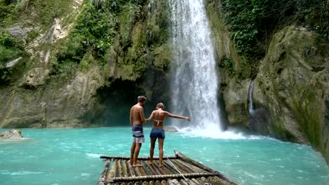 Young-couple-being-affectionate-at-beautiful-tropical-waterfall-in-the-Philippines-enjoying-vacations-and-freedom.-People-travel-love-concept