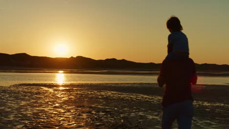 Silueta-del-padre-paseando-con-el-hijo-sobre-sus-hombros-en-la-playa