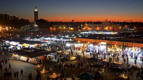 Multitudes-de-personas-que-pasan-por-el-mercado-en-la-plaza-Jemaa-el-Fnaa-en-Marrakech,-Marruecos-justo-después-de-la-puesta-del-sol.-4K,-UHD