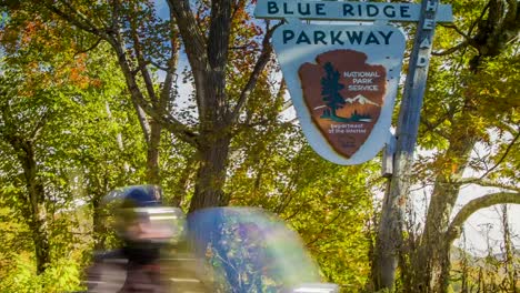 Motocicletas,-pasando-nostálgico-signo-de-Blue-Ridge-Parkway,-cerca-de-la-ciudad-de-Asheville,-Carolina-del-Norte