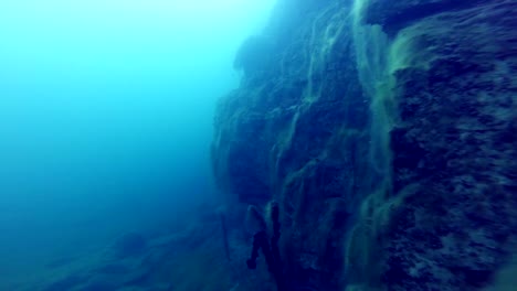 Freediver-explorar-un-lado-de-un-submarino-del-acantilado-en-una-cantera