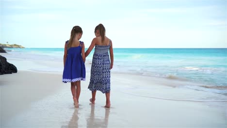 Little-girls-walking-by-the-sea-on-the-white-beach.-Kids-on-beach-vacation-in-the-evening