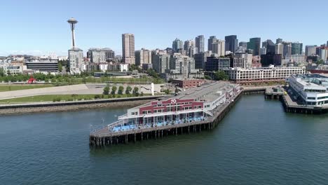 Aerial-Dolly-Across-Downtown-Seattle-Buildings-and-Waterfront-Pier-70-on-Sunny-Day-with-Blue-Sky