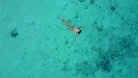 Vista-aérea-de-una-atractiva-mujer-en-un-bikini-flotando-en-el-mar-de-aguas-cristalina.-Bonita-hermosa-chica-nadando-en-el-Océano-Índico