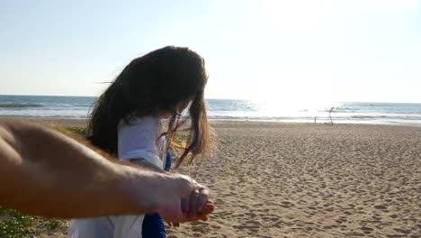 Girl-holding-male-hand-and-running-on-tropical-exotic-beach-to-the-ocean.-Follow-me-shot-of-young-woman-pull-her-boyfriend-on-the-sea-shore.-Summer-vacation-or-holiday.-Point-of-view.-POV