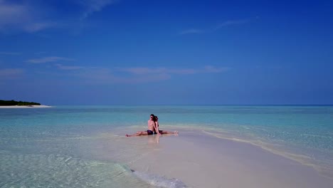 v03868-fliegenden-Drohne-Luftaufnahme-der-Malediven-weißen-Sandstrand-2-Personen-junges-Paar-Mann-Frau-romantische-Liebe-auf-sonnigen-tropischen-Inselparadies-mit-Aqua-blau-Himmel-Meer-Wasser-Ozean-4k