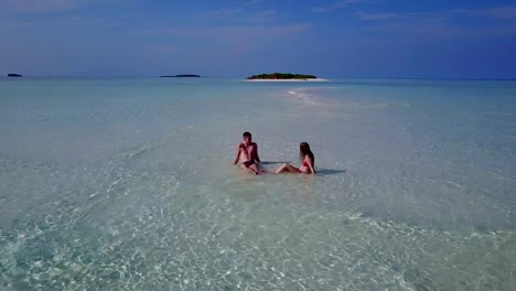 v04029-fliegenden-Drohne-Luftaufnahme-der-Malediven-weißen-Sandstrand-2-Personen-junges-Paar-Mann-Frau-romantische-Liebe-auf-sonnigen-tropischen-Inselparadies-mit-Aqua-blau-Himmel-Meer-Wasser-Ozean-4k