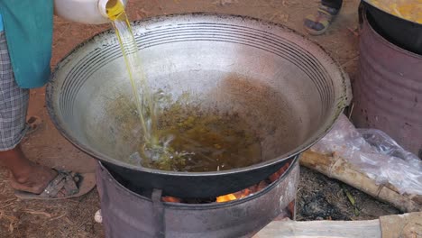 Frau-gebratene-Öl-in-einem-großen-Outdoor-Wok-kochen,-Frittieren-Huhn-gießen