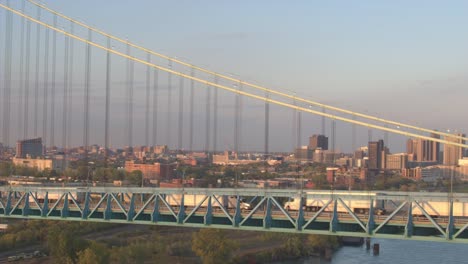 AERIAL:-Semi-trucks-transporting-goods-crossing-the-highway-bridge-at-sunrise