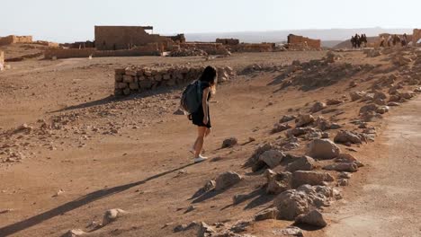 Niña-con-mochila-explora-ruinas-desierto.-Viajero-mujer-bastante-Europea-camina-entre-paisaje-antiguo.-Masada-Israel-4K