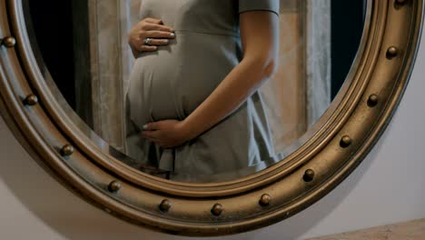 Pregnant-woman-touching-belly,-mirror-reflection